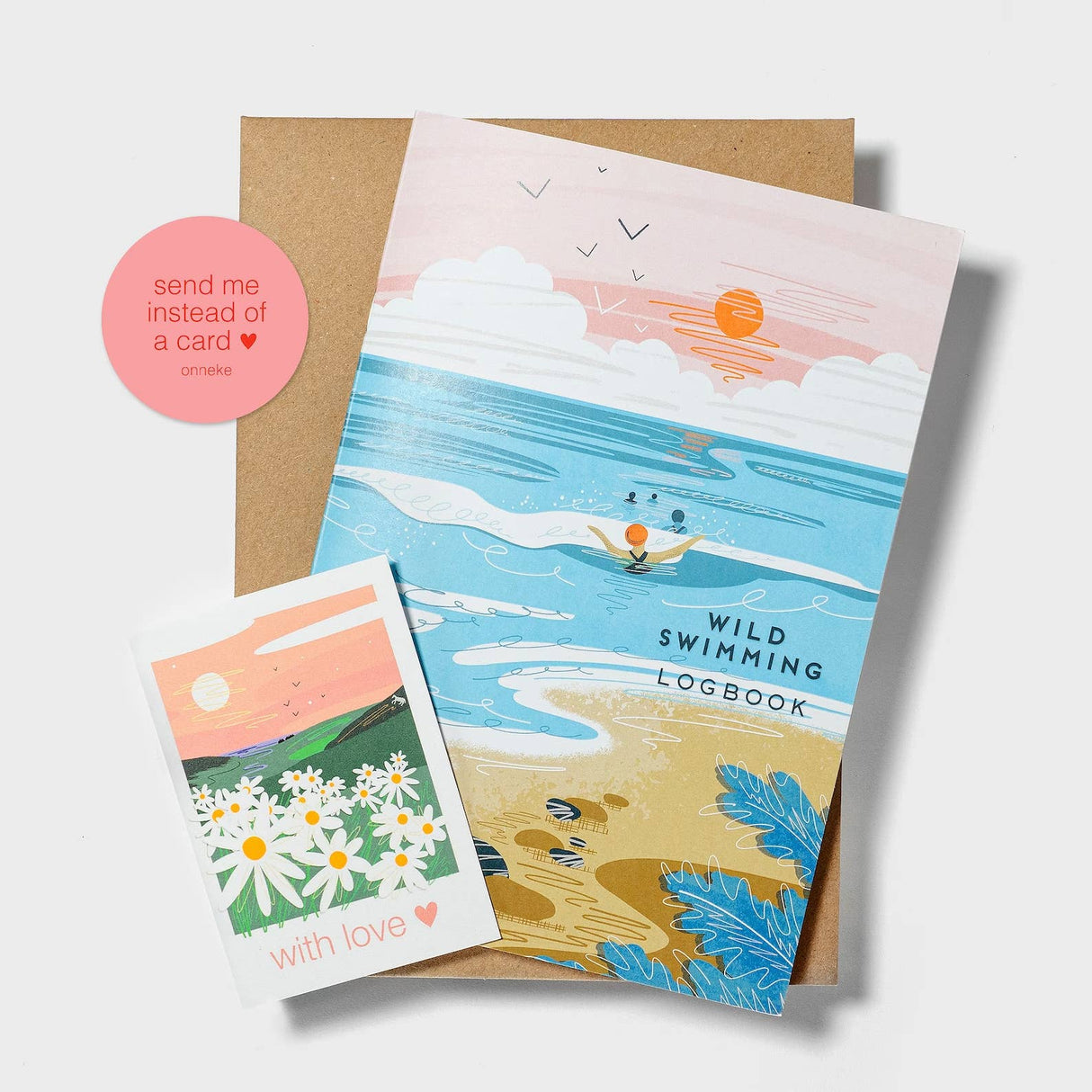 The "Wild swimming logbook into the sea - sea swimming notebook" is a colorful gift made from recycled paper, featuring an illustrated beach scene, a daisy card with "with love," and a round sticker saying "send me instead of a card ♥.
