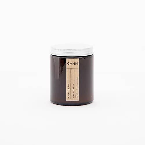 A brown glass jar with a white lid labeled "Amalfi Coast Amber," crafted with vegan soy wax. The minimalist design highlights the eco-friendly vibe, set against a plain white background.
