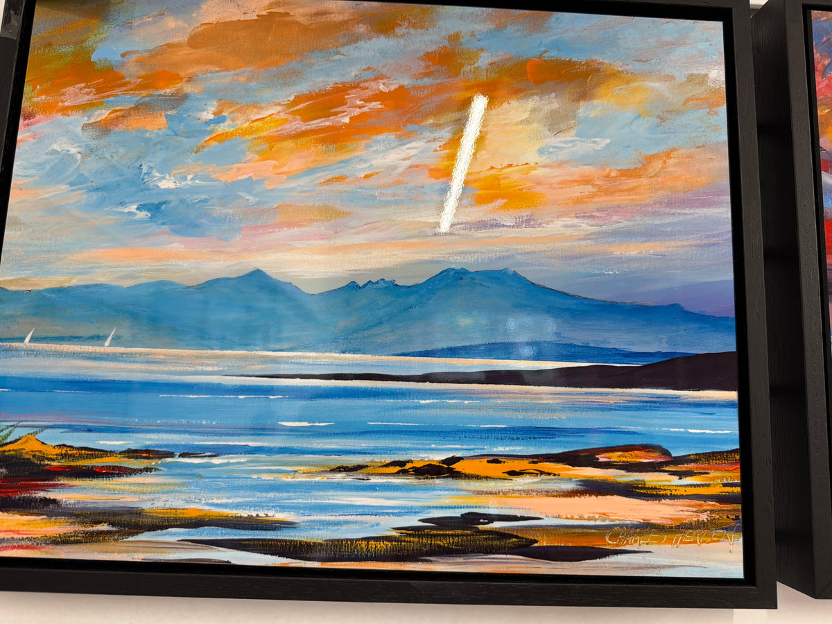 The “Distant Arran Ceramic Tile” features a vibrant landscape painting inspired by Charles Herbert, showcasing distant mountains beneath a striking orange and blue sky with a streak of white clouds. Reminiscent of classic Arran landscapes, the design includes a serene body of water and a colorful shoreline in the foreground, capturing scenes often depicted on decorative ceramic tiles.