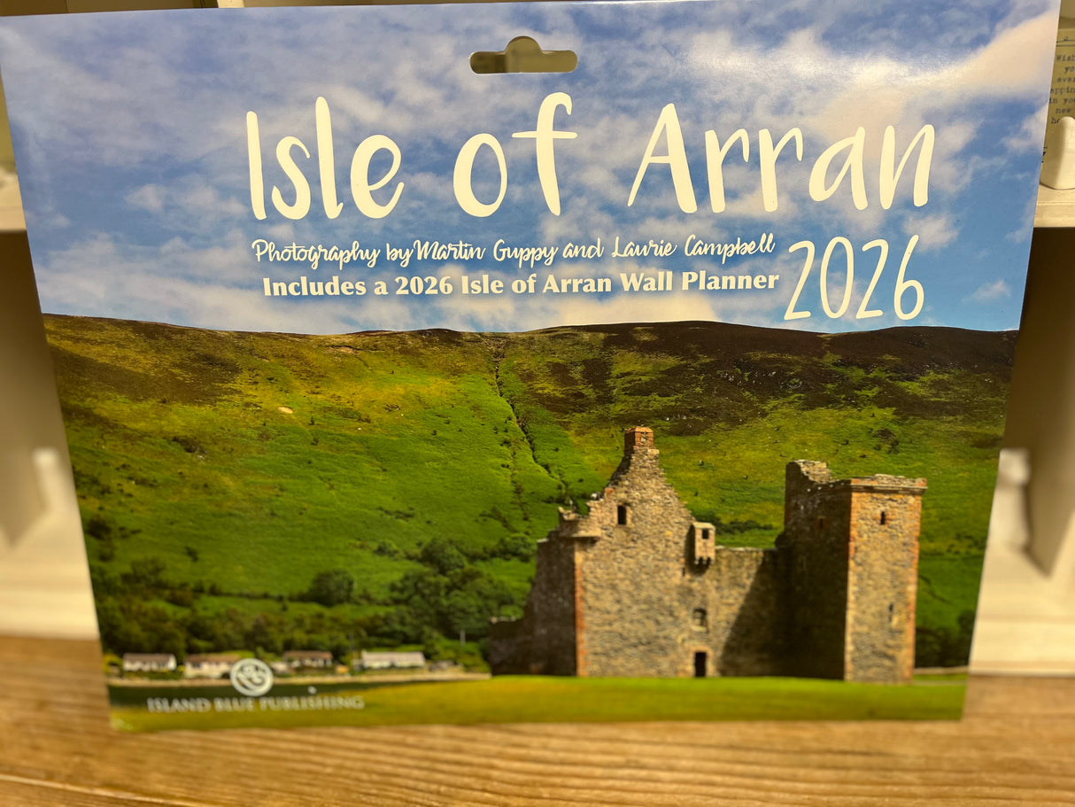 The cover of the Isle of Arran 2026 Landscape Calendar features a scenic photo of a lush green hill topped with an old stone castle ruin beneath a partly cloudy blue sky.