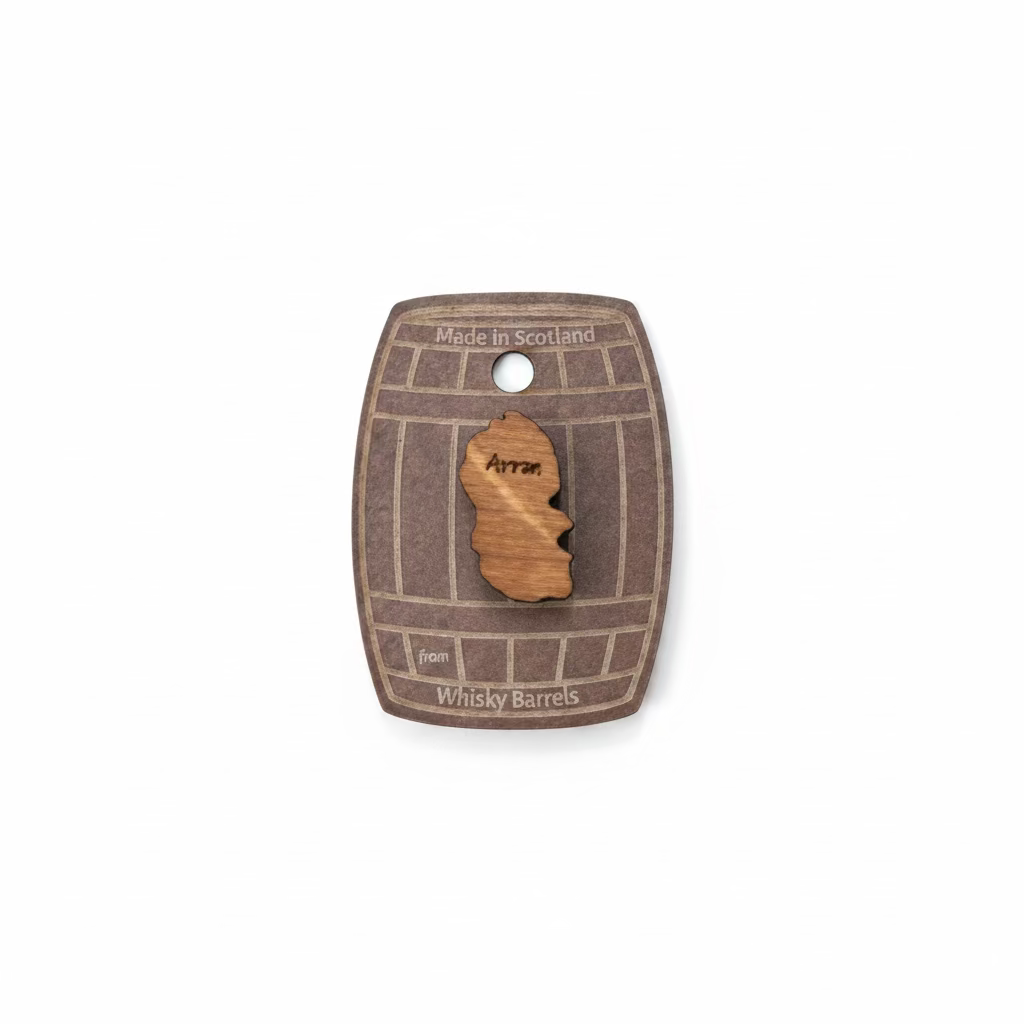 The Arran Pin Badge Made from Whisky Barrels features a wooden Isle of Arran shape mounted on a card resembling a whisky barrel, reading "Made in Scotland from whisky barrel wood"—a unique Scottish souvenir.