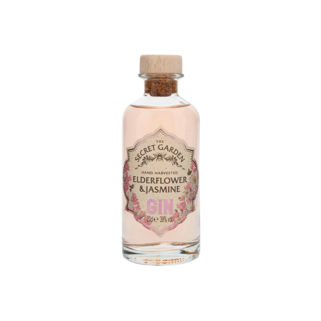 A clear glass bottle of Midi Elderflower & Jasmine Gin from Secret Garden Distillery has a cork stopper and a floral label with pink and gold text, showcasing this elegant gin's name and its 39% vol alcohol content.