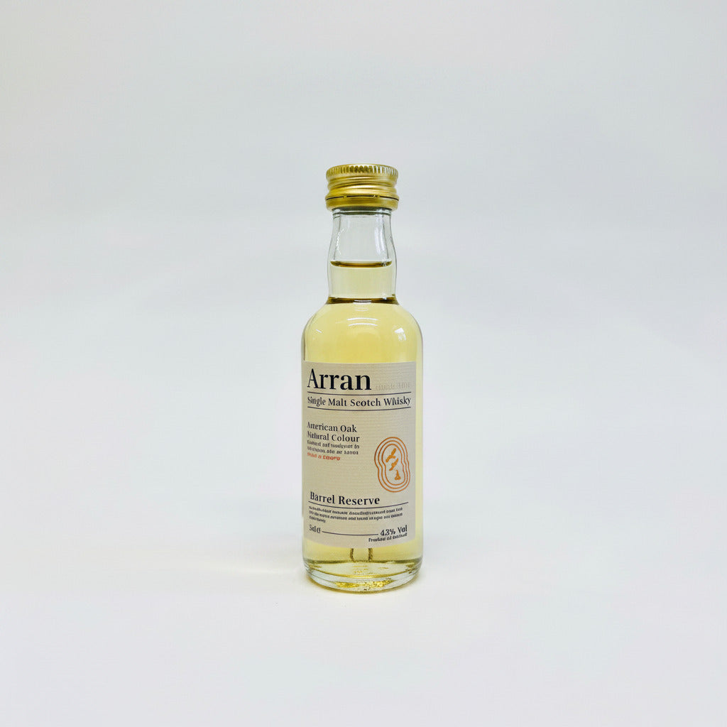The Arran Barrel Reserve Single Malt Whisky Miniature 5cl showcases a golden cap, with its transparent glass revealing a pale amber liquid that is sure to entice any whisky lover. The label prominently features the terms "American Oak" and "Natural Colour," and it has an alcohol content of 43%.