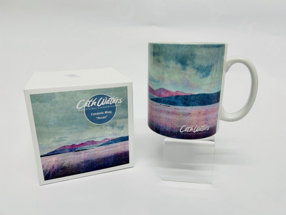 A ceramic mug and its box, both featuring a serene watercolor-style landscape with mountains, a lake, and soft pastel colors. The mug and box are branded "Celt Waters.
