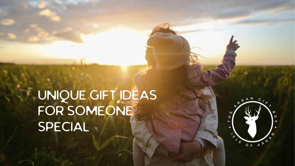 A person carrying a child points towards the sunset in a field. Text reads "Unique Gift Ideas for Someone Special." The Arran Gift Box logo is visible in the corner.