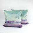 Two Arran Velvet Cushions with a soft watercolor-style landscape in pastel green, purple, and pink, featuring mountains and water, showcase contemporary Scottish design against a plain white background.