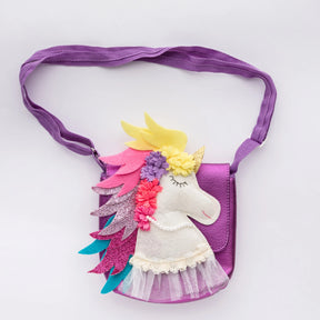 The Children's French Unicorn Bag is a small purple bag with a felt unicorn design, featuring a yellow horn, multicolored mane, closed eyes, flowers, lace, pearls, and an adjustable strap for comfort.