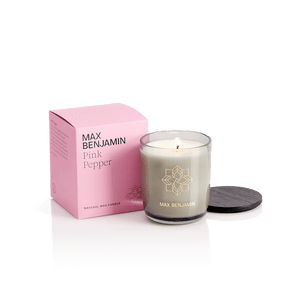 The Max Benjamin Pink Pepper Candle, hand-poured in Ireland from natural wax, is displayed lit in a glass jar with its pink box and black lid on a white background.