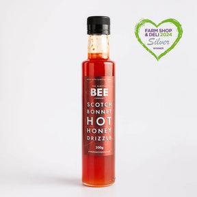 A bottle of Scotch Bonnet Hot Honey Drizzle - Spicy Hot Honey is set against a white background, featuring a green heart-shaped Farm Shop & Deli 2024 Silver Winner badge in the top right corner.