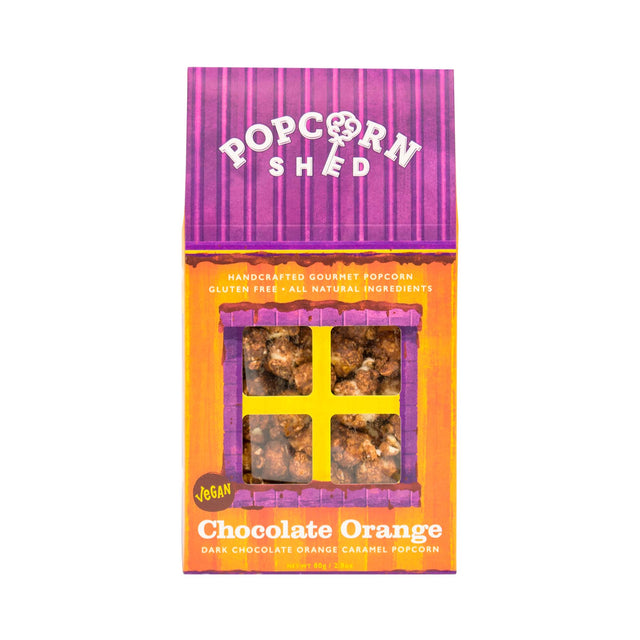 A box of Vegan Chocolate Orange Gourmet Popcorn Snack, featuring a purple and orange design, a window revealing the chocolate orange popcorn inside, and labels that read “Vegan” and “Handcrafted Gourmet Popcorn.”.