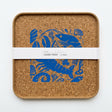 Square organic Seafood Platter Cork Serving Tray featuring a blue illustrated pattern of shrimp and shells, wrapped in a paper band labeled “Cork Tray.”