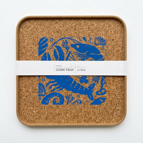 Square organic Seafood Platter Cork Serving Tray featuring a blue illustrated pattern of shrimp and shells, wrapped in a paper band labeled “Cork Tray.”