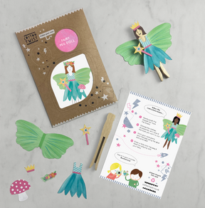 The Make Your Own Fairy Peg Doll kit features a brown packet, paper wings, a mushroom, a crown, vibrant instructions, a wooden peg, and a small wand—all arranged on a white surface. This eco-friendly craft kit is ideal for inspiring creativity and helping little ones develop fine motor skills.