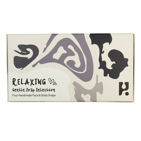 The Relaxing Soap Gift Set is a rectangular box labeled "Relaxing Gentle Soap Selection: Four Handmade Face & Body Soaps," featuring abstract black and gray shapes on a cream background—a luxurious vegan set crafted in Scotland.