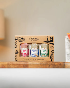 The Eden Mill Gift Set, featuring miniatures of Love Gin, Original Gin, and Golf Gin, is elegantly displayed on a wooden surface with a soft backdrop, showcasing the unique craftsmanship of St Andrews gin.
