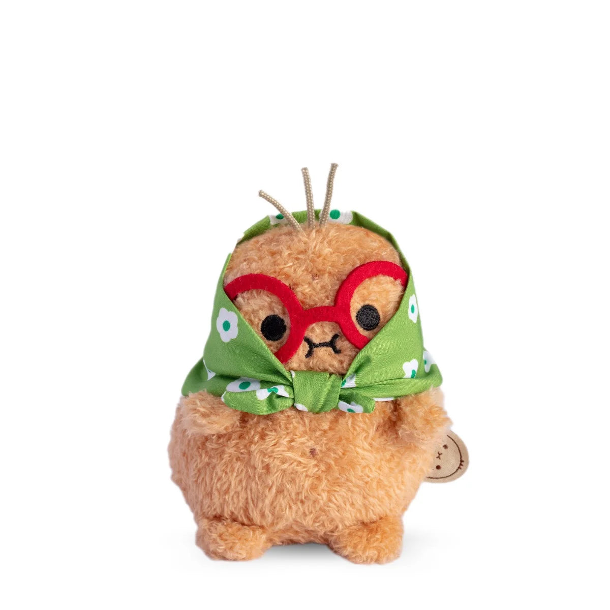 A Noodoll Ricespud Grandma plush stands against a white background, featuring light brown fur, red glasses, a green headscarf with white flowers tied under its chin, and two small rope-like strands on its head.