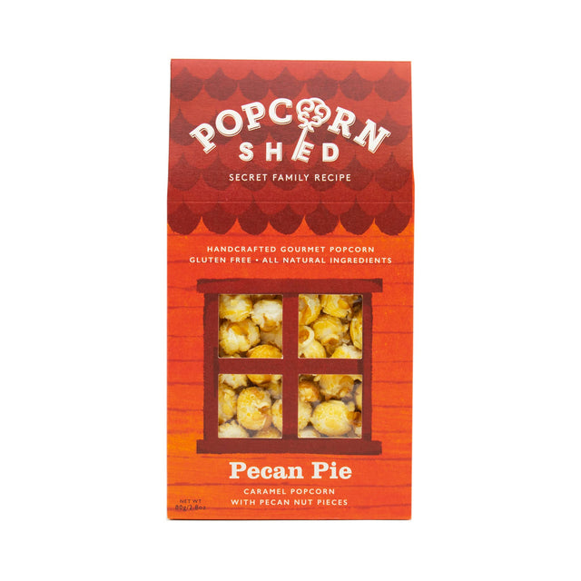 A red box of Pecan Pie Gourmet Popcorn Snack Box, featuring a window design that reveals the delicious pecan caramel popcorn inside. The label highlights that it is gluten-free, handcrafted popcorn with pieces of pecan nuts.