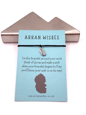 A blue card titled "Arran Wishes" displays an Arran Shaped Charm Wish Bracelet with a black cord and silver Isle of Arran charm on a metal holder. The card shows a wish-making message and a website link at the bottom.