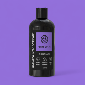 The 250ml Parma Violet Bubble Bath by Glasgow Soap Company comes in a black bottle with eco-conscious packaging, vegan friendly, cruelty free, and SLS/paraben-free symbols. Presented against a purple background—luxury bath gift.