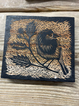 East of India Decorative Wooden Block featuring a natural wood finish and a burnt-wood relief carving of a bird perched on a leafy branch.
