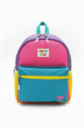 The Hairy Coo Kids Backpack has pink, purple, teal, and yellow panels with a blue front pocket, "HAIRY COO" label, and a small highland cow graphic in the lower right corner on a white background.