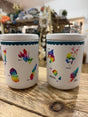 The Scottish Islands Ceramic Jars set features two white ceramic canisters for tea and coffee, each decorated with vibrant watercolor-style maps and island names, perfect for adding charm to any kitchen or shop display.