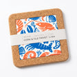 Seafood Platter Cork and Tile Trivet featuring a square cork and earthenware design with a central seafood print in blue and orange, secured with a paper band.