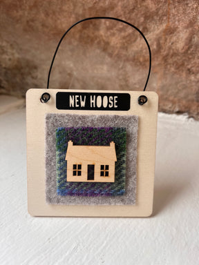 The Home Sweet Home Wooden Hanging Sign — All That Glitters is a small, handmade Scottish sign with a wire handle and wooden house cutout on felt, labeled "NEW HOOSE"—perfect as a housewarming gift.