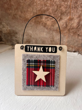 The Thank You Wooden Hanging Sign — All That Glitters is a small square sign with a black wire handle, "THANK YOU" text, red plaid patch edged in gray felt, and wooden star—an ideal handmade appreciation gift from Scotland.