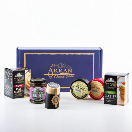 A Simply Arran Hamper containing a box of oatcakes, a jar of red onion chutney, a block of Arran cheese, two round cheeses, and a box of oaty biscuits.