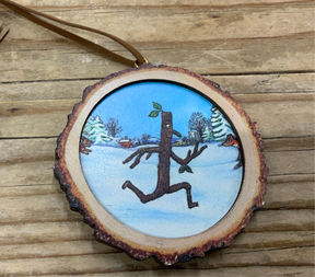 The Stickman Wood Log Decoration features a round wooden ornament painted with a stick figure running through snowy trees and a fox. Complete with a brown hanging ribbon, it’s a charming festive addition to your tree.