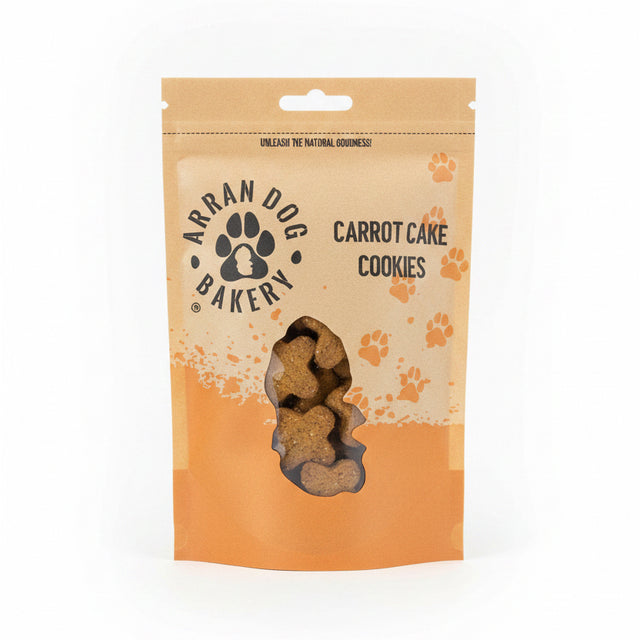 A brown and orange resealable pouch labeled "Carrot Cake Arran Dog Biscuits" displays bone-shaped natural dog treats through a clear window at the bottom, with paw prints decorating the packaging.