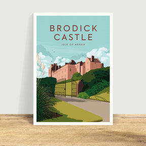 Catriona Tod Brodick Castle Print features a vibrant scene of Brodick Castle on the Isle of Arran, with its pinkish towers surrounded by lush greenery beneath a blue sky dotted with clouds and birds.