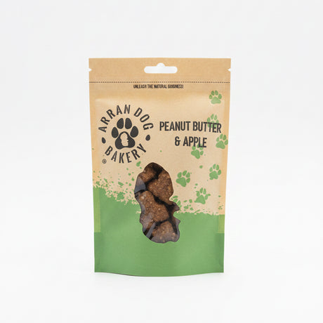 A brown and green pouch of Apple & Peanut Butter Arran Dog Biscuits, featuring a paw print logo and clear window displaying bone-shaped treats with apple inside.