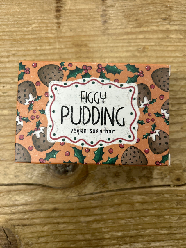 A box of Figgy Pudding Vegan Soap Bar, featuring figgy pudding, holly leaves, and berries artwork on a wooden background.