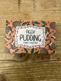 A box of Figgy Pudding Vegan Soap Bar, featuring figgy pudding, holly leaves, and berries artwork on a wooden background.