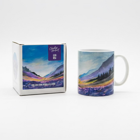 The Glen Rosa Mug and its box feature a colorful landscape painting with mountains, trees, and a vibrant sky, set against a plain white background.