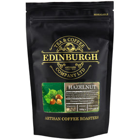 A 200g resealable black bag of Hazelnut Ground Coffee by Edinburgh Tea & Coffee Company, featuring gold and green text, a logo, hazelnuts on the front, and labels noting strength and roast date.