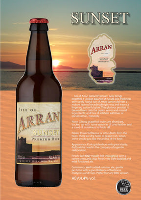 Arran Sunset Premium Beer stands before a tranquil seaside sunset. Its label is clear, with text beside the bottle describing this refreshing ale’s unique flavor and aroma against a scenic water backdrop.