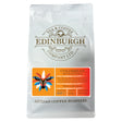 A 200g bag of Columbian coffee beans from Edinburgh Tea & Coffee Company. This traditional coffee features an orange label adorned with a vibrant mask illustration and product details, emphasizing the signature caramel notes characteristic of Huila coffees.
