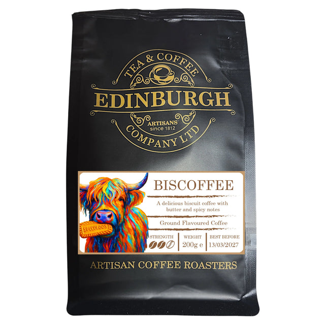 A 200g black bag of Biscoffee from the Edinburgh Tea & Coffee Company, adorned with a colorful cow illustration. The label describes this biscuit coffee as ground coffee with buttery, spicy notes and hints of biscuit. Best before: 13/03/2027.