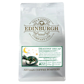 A 200g white bag of Dragons Decaf from Edinburgh Tea & Coffee Company, adorned with a dragon illustration and a label emphasizing the Swiss Water decaffeination process. This decaf coffee features subtle caramel and peanut notes, with a best before date of 07/01/2027.