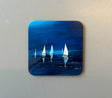 A small CHARLES HERBERT COASTER by Charles Herbert depicts several sailboats with white sails gliding on a calm, dark blue sea at night. The sailboats are reflected in the water under a serene night sky.