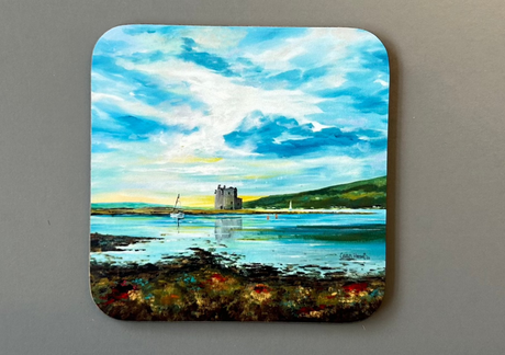 Discover the CHARLES HERBERT COASTER by Charles Herbert, showcasing a serene coastal landscape with a majestic castle by the water's edge. The sky features blue and white clouds, with rolling hills in the background. The foreground beautifully captures the shore adorned with patches of brown and green vegetation.