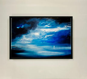 A Blue Yonder Ceramic Tile featuring a dramatic seascape with deep blue water, swirling white clouds, and a distant sailboat—evoking Arran landscapes—hangs on a plain, light-colored wall.