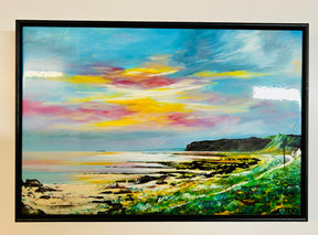 The Bennan Head Ceramic Tile features a coastal landscape at sunset, inspired by Arran, with a rocky shoreline, calm water reflecting vibrant yellow, pink, and blue skies, and green cliffs on the right.