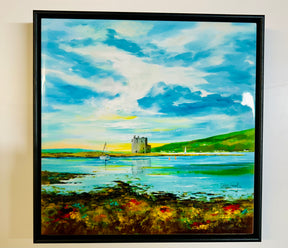 Lochranza Castle Ceramic Tile featuring a coastal scene inspired by Arran, with an island castle, sailboats on blue water, green hills, and a vibrant foreground of grass and flowers beneath a bright sky.