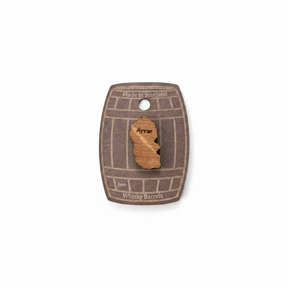The Arran Pin Badge Made from Whisky Barrels features a wooden Isle of Arran shape mounted on a card resembling a whisky barrel, reading "Made in Scotland from whisky barrel wood"—a unique Scottish souvenir.