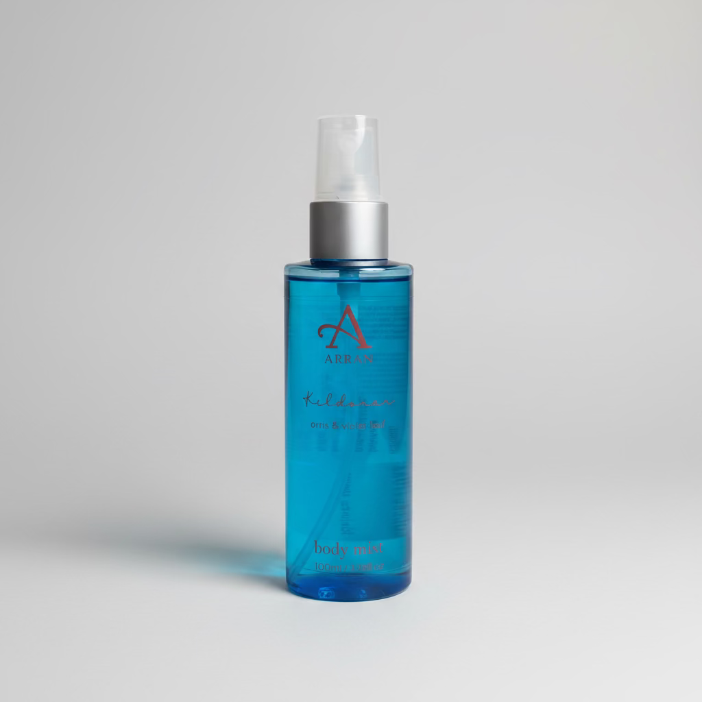 A blue bottle of Kildonan Body Mist 100ml – ARRAN Sense of Scotland, infused with a delicate floral fragrance inspired by the Isle of Arran, stands upright with a clear plastic spray top on a plain light gray background.