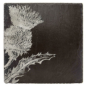 Single Slate Coaster - Thistle: A black slate coaster featuring a white etched thistle flower with jagged leaves in the lower left corner; the remaining surface is plain.